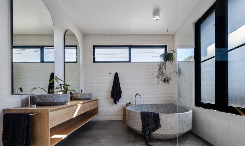 spacious bathroom featuring a large round freestanding bath in terazzo