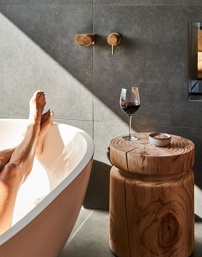 a person enjoying a bath in the sun and a glass of red wine