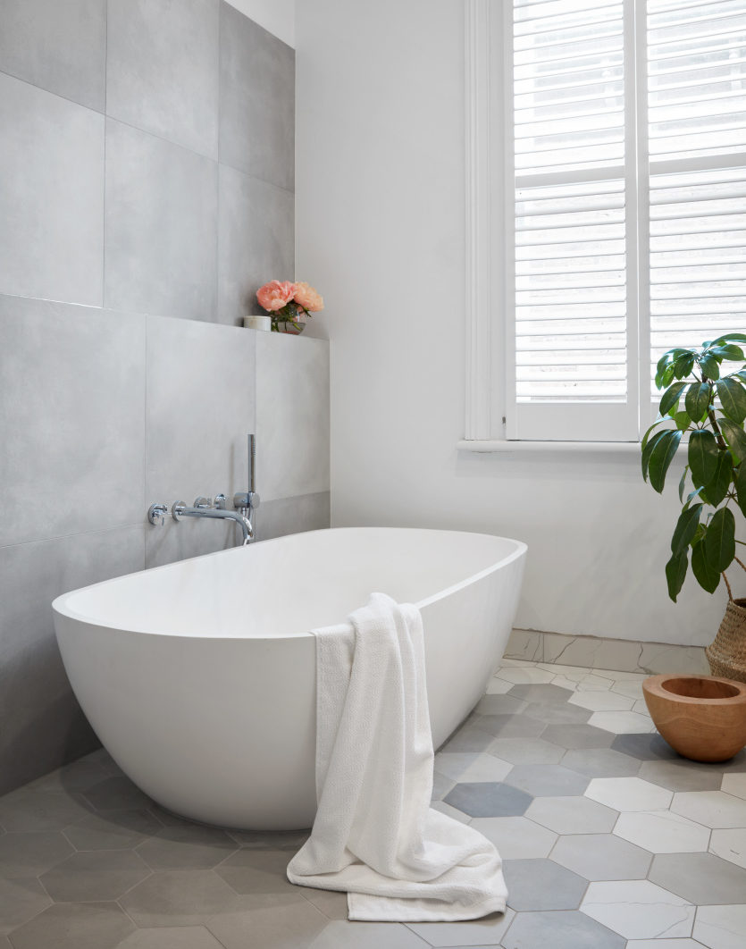 A grey residential bathroom with an apaiser Sublime Bath with a white towel thrown over it